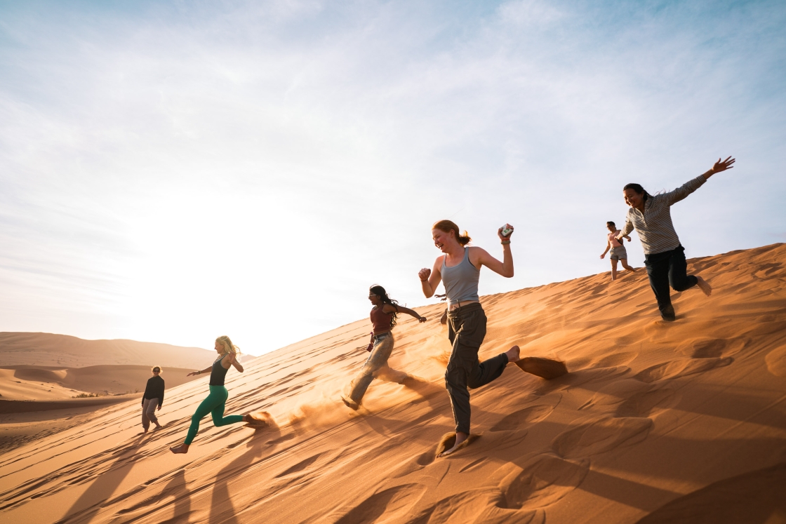 Students running down sand dunes