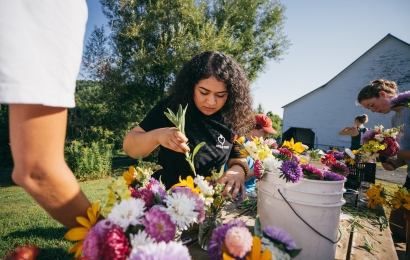 Student arranging flowers in buckets at the Organic Farm