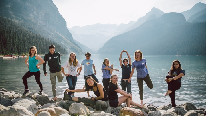 Group of students stretching on rocks by a lake