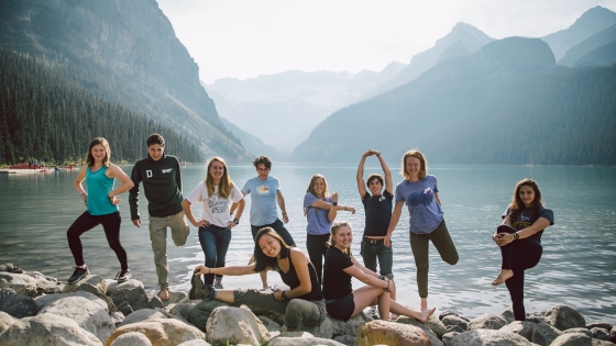 Group of students stretching on rocks by a lake