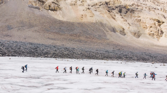 people walking across a glacier