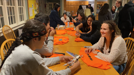 Students decorating orange shirts around a table
