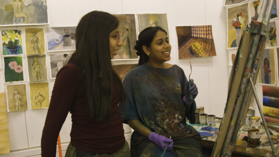 Two women smiling at a canvas in the art studio