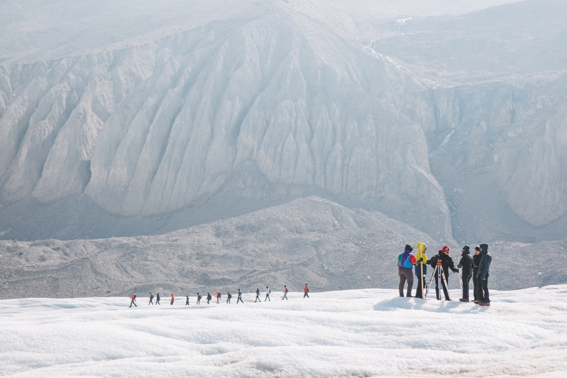 Students hiking on a glacier in single file.
