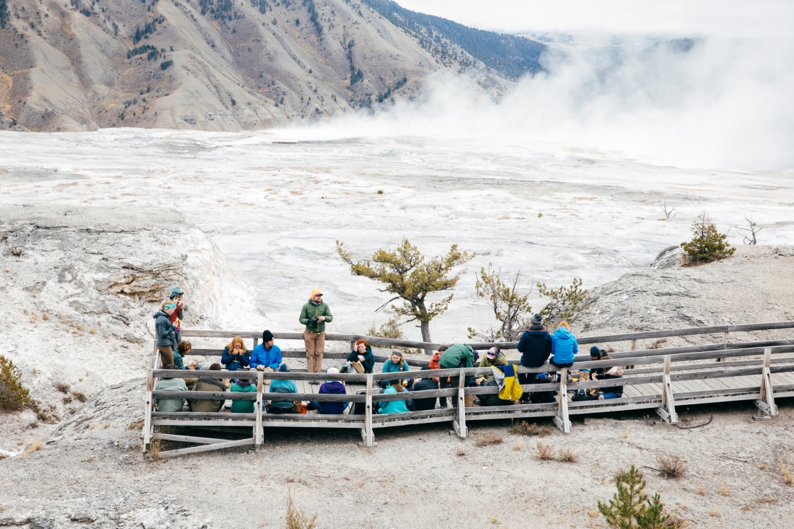 Students sitting and eating on a wooden walkway in Yellowstone National Park.