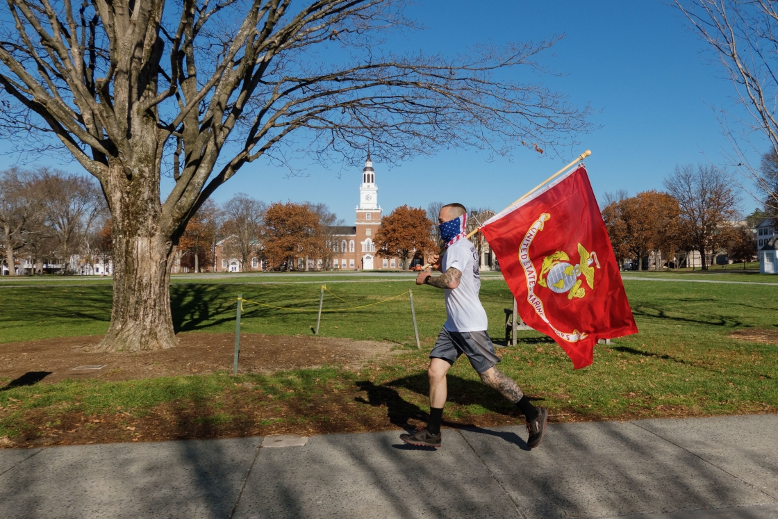 Jason Mosel carrying the marines flag in front of the library