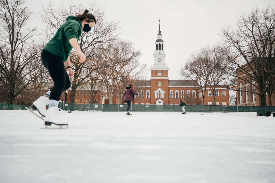 Three people ice skating in front of Baker-Berry library