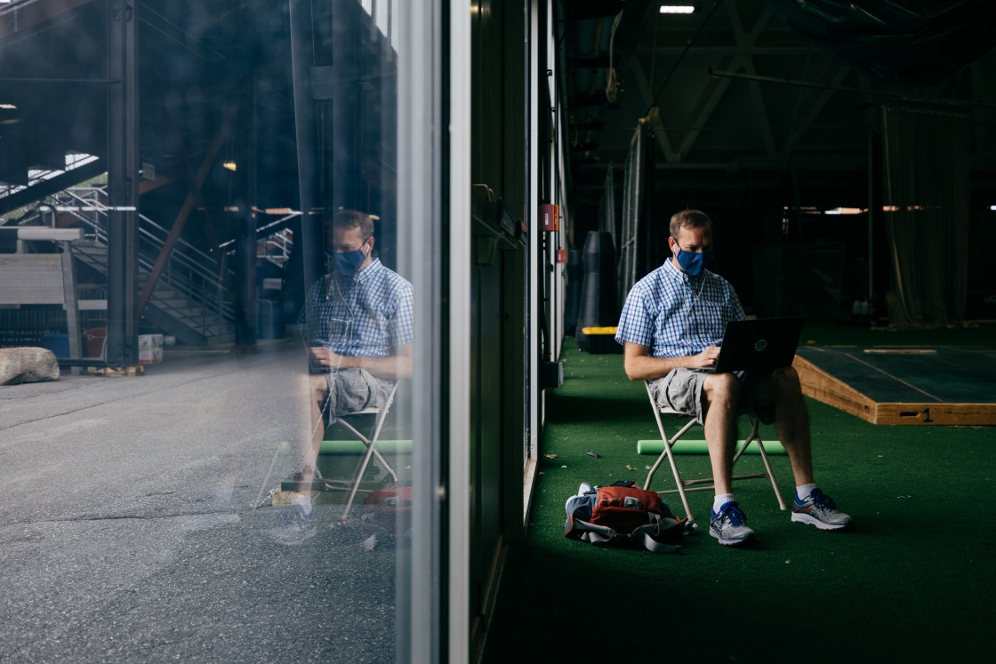 Person sitting in a chair with a laptop and their exact reflection in the window