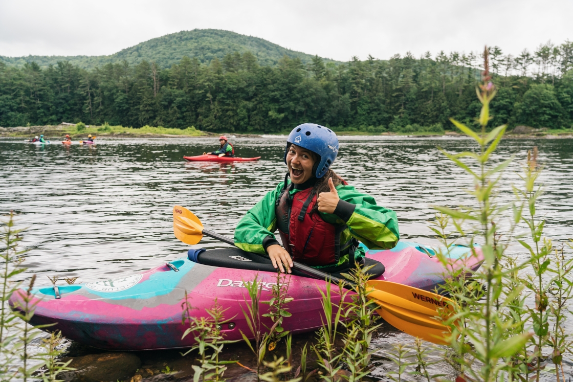 Person in white water kayaking smiling with a thumbs-up