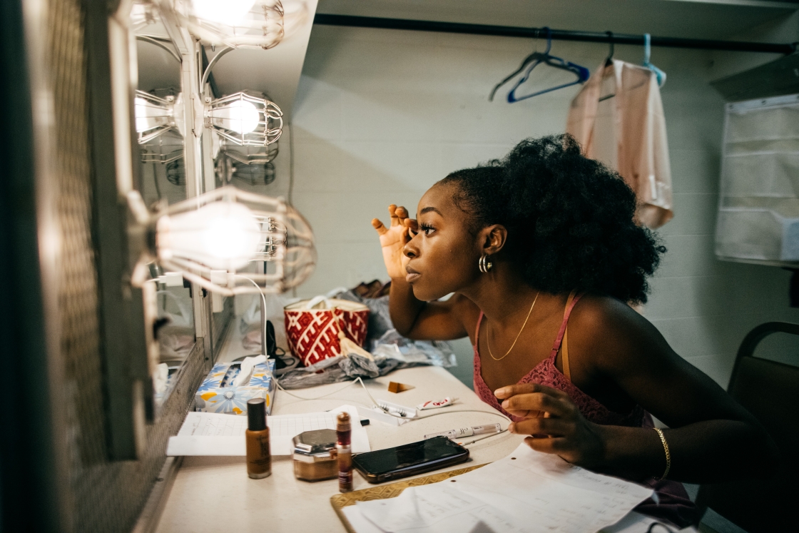 A woman applying makeup in front of a vanity