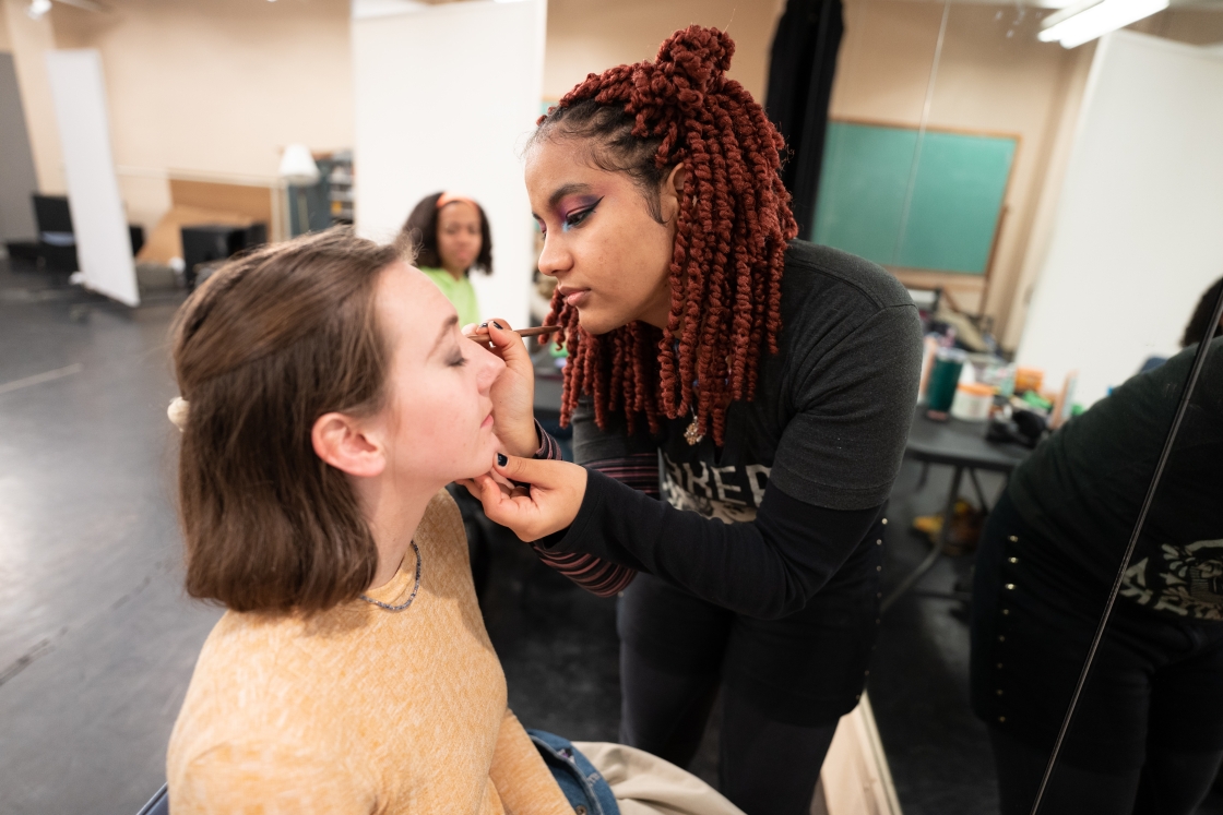 Student applying make up to Rent actor.