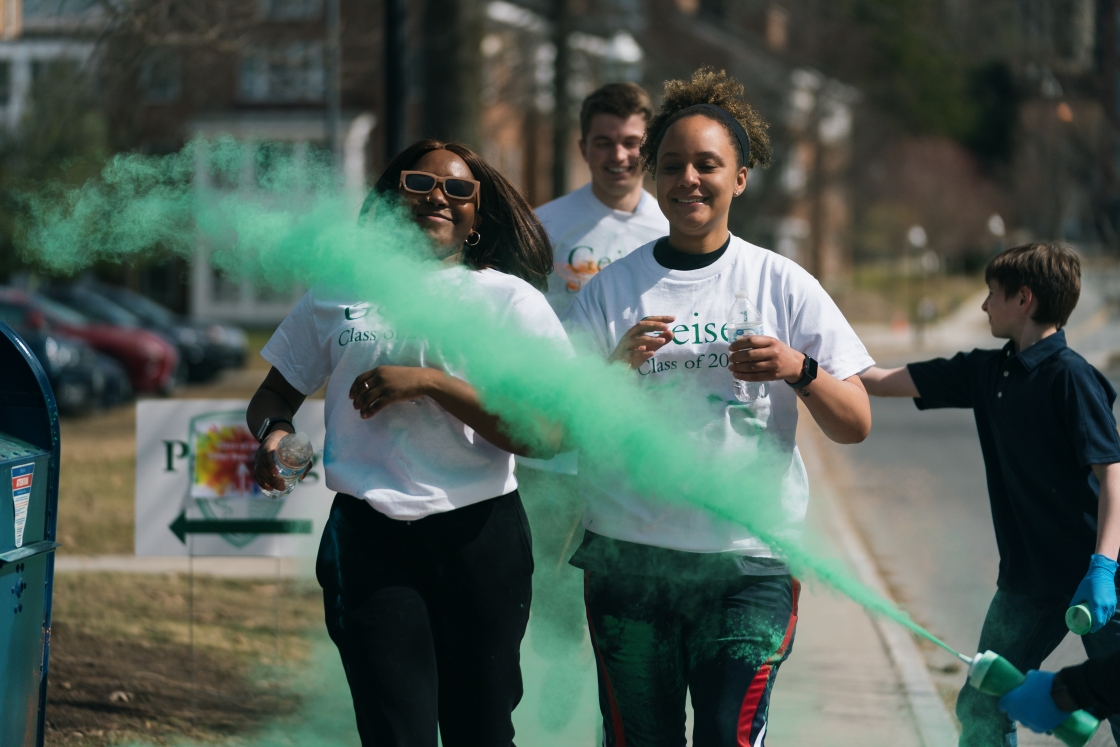 Two women running and getting sprayed with green powder