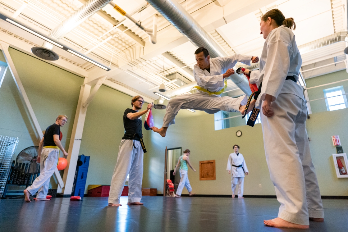 Students practicing a split kick in traditional uniforms