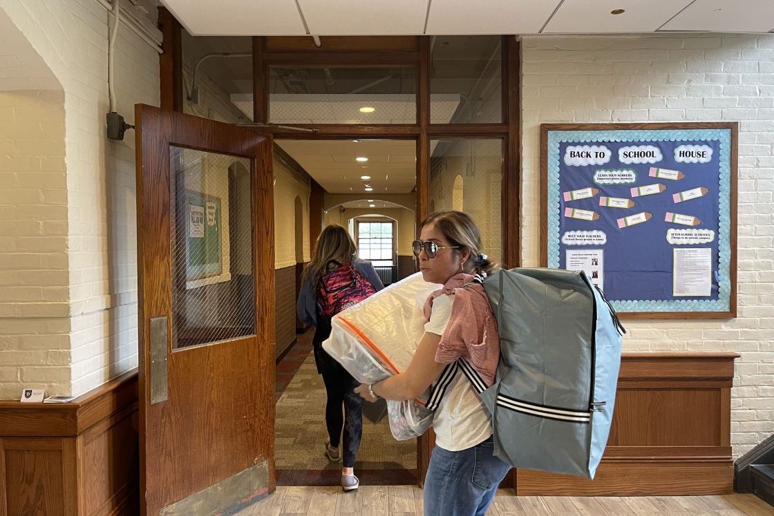 Students carry heavy bags full of bedding into the dorm