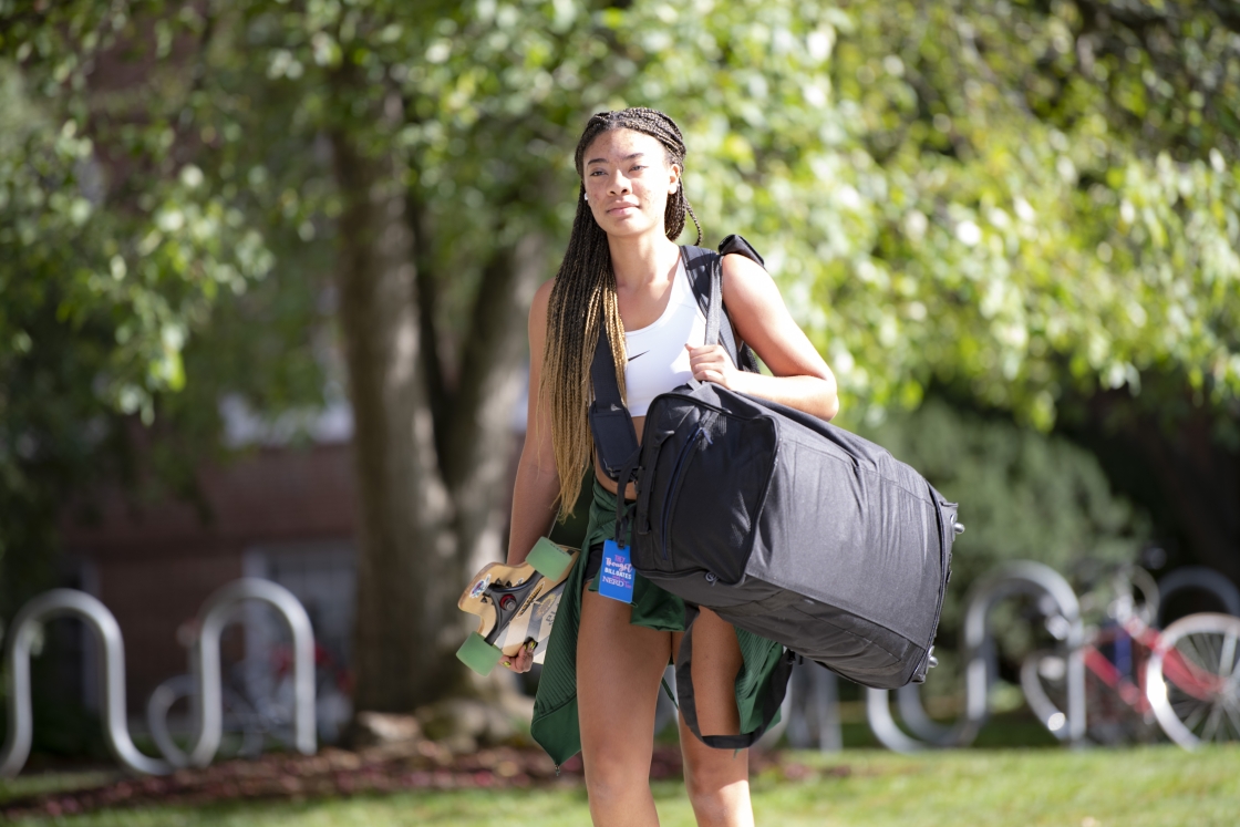 Student carries large black luggage bag