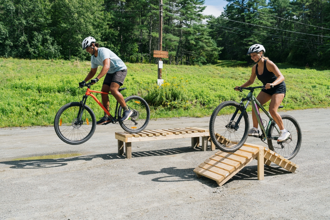 Two mountain bikers going over obstacles