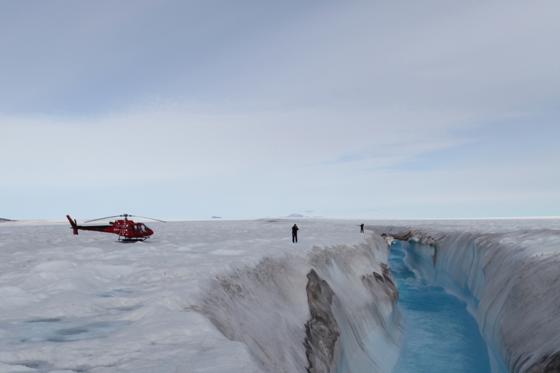 A red helicopter and two scientists on an iceberg in Greenland
