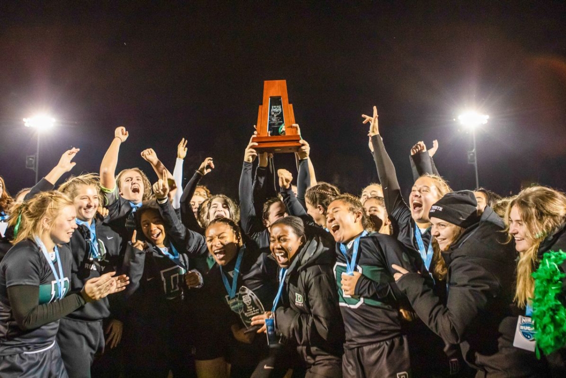 Women's rugby team holding trophy and cheering