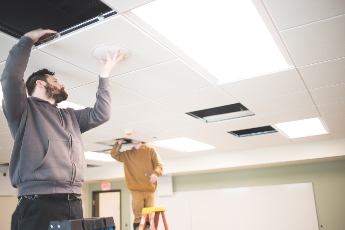 Two people installing technology into the ceiling in Silsby