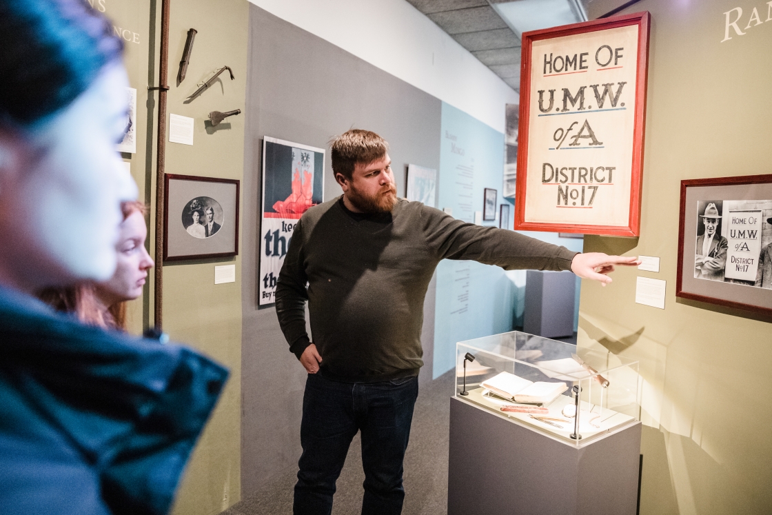 Person pointing to a framed black and white photograph in a museum