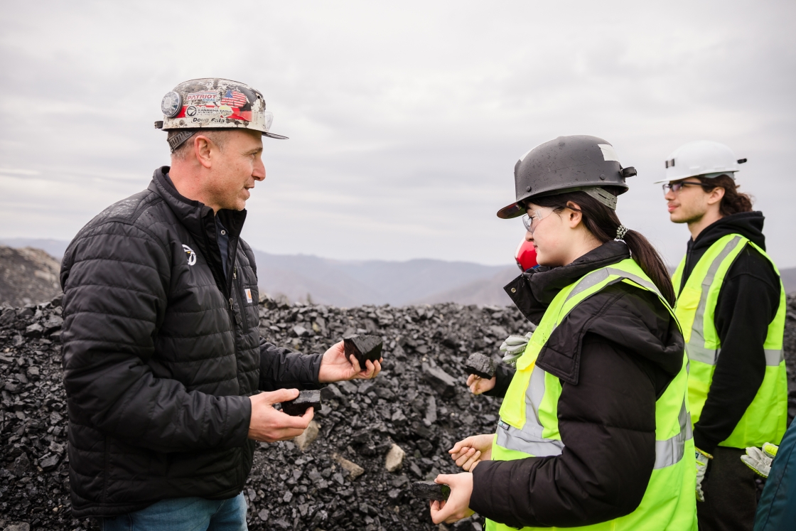 Doug Fala speaks to Constance Legrand and Luc Cote, wearing safety vests and hard hats