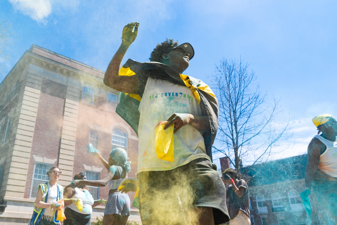 Student dancing with yellow powder paint flying in the air