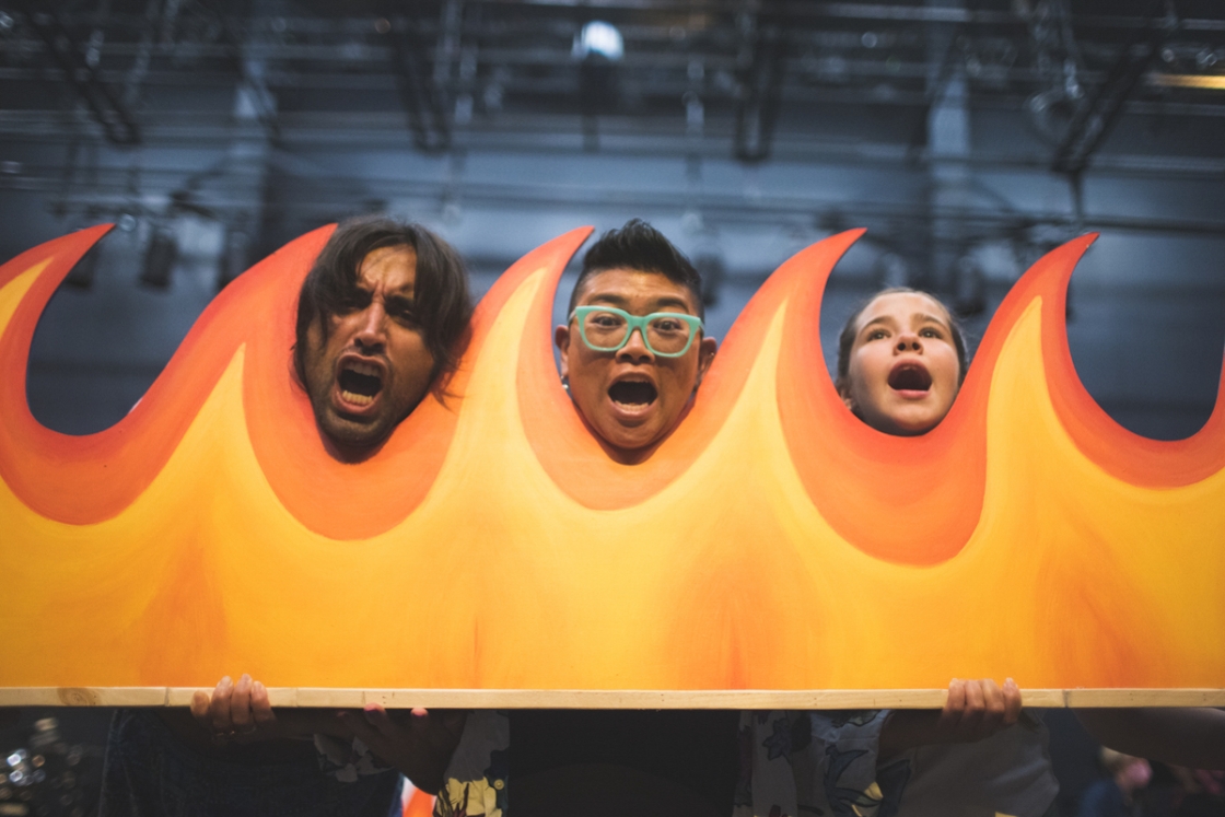 Three people posing by flame set piece