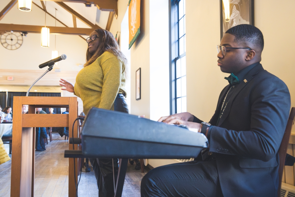 Two students lead attendees in a song