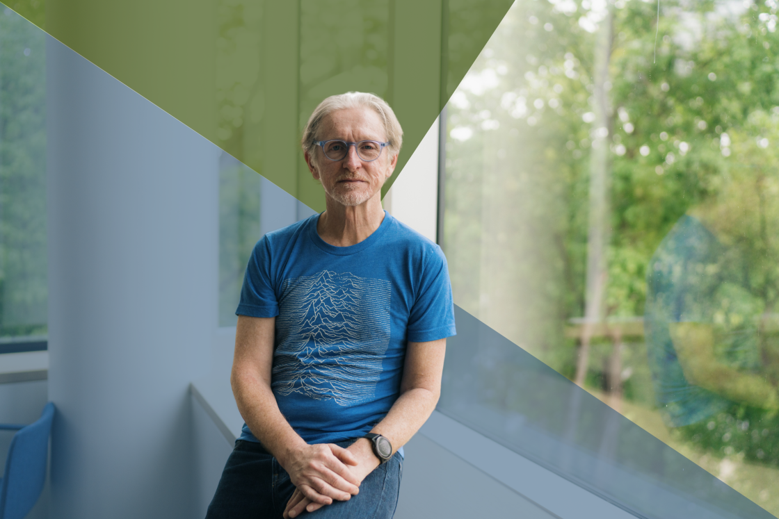 Andrew Campbell seated by a window in a blue t-shirt and glasses