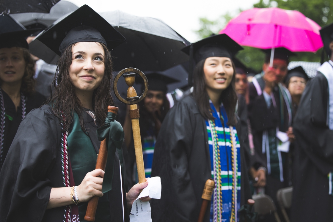Graduates at Dartmouth Commencement stand in the rain with umbrellas