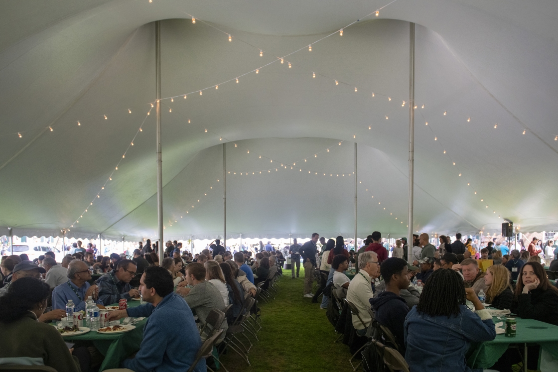 Dartmouth families gather under a large tent with strings of light