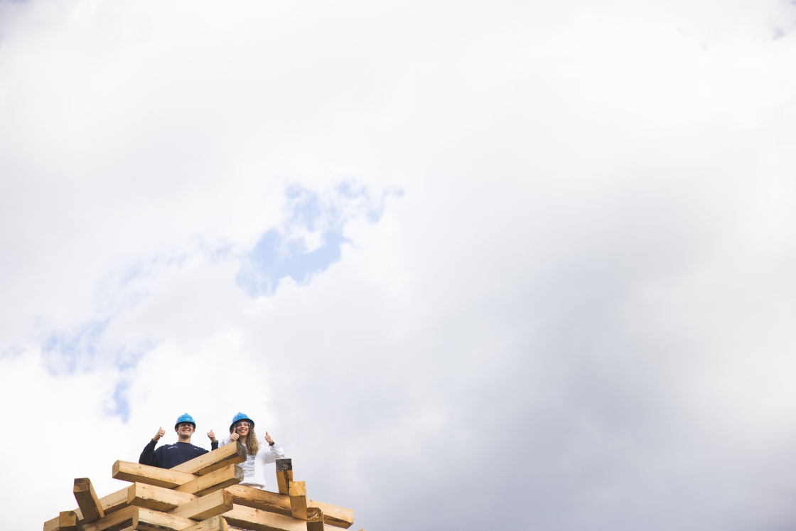 Builders standing on stack of wood