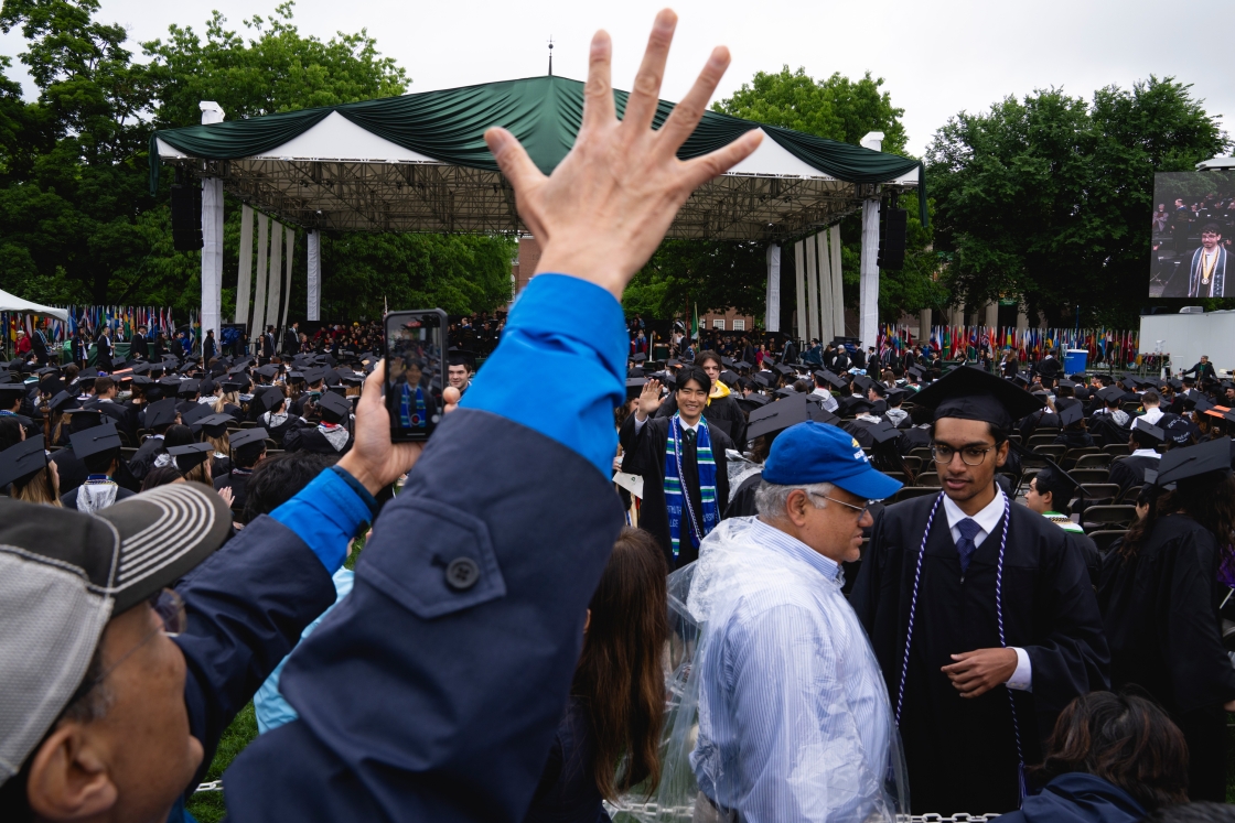 A man raises his hand to grab the attention of a graduate