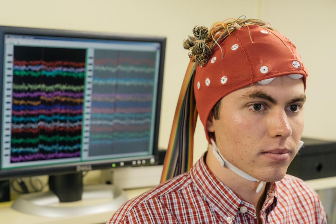 A student wears a cap fitted with electrodes for a reading experiment