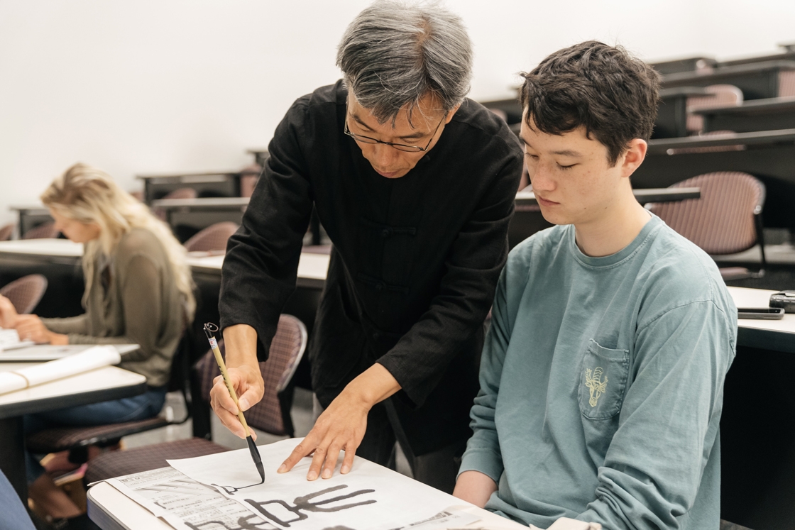A professor and student work on Chinese calligraphy