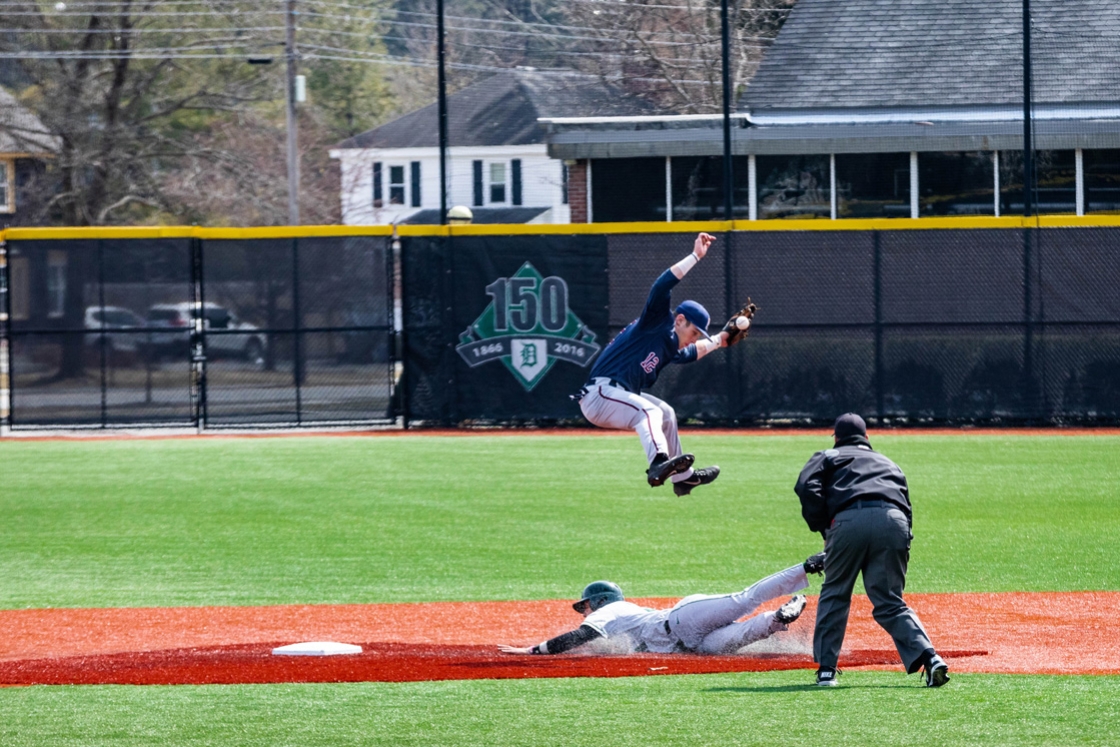 A Dartmouth baseball player jumps high, avoiding a sliding member of the other team into second base