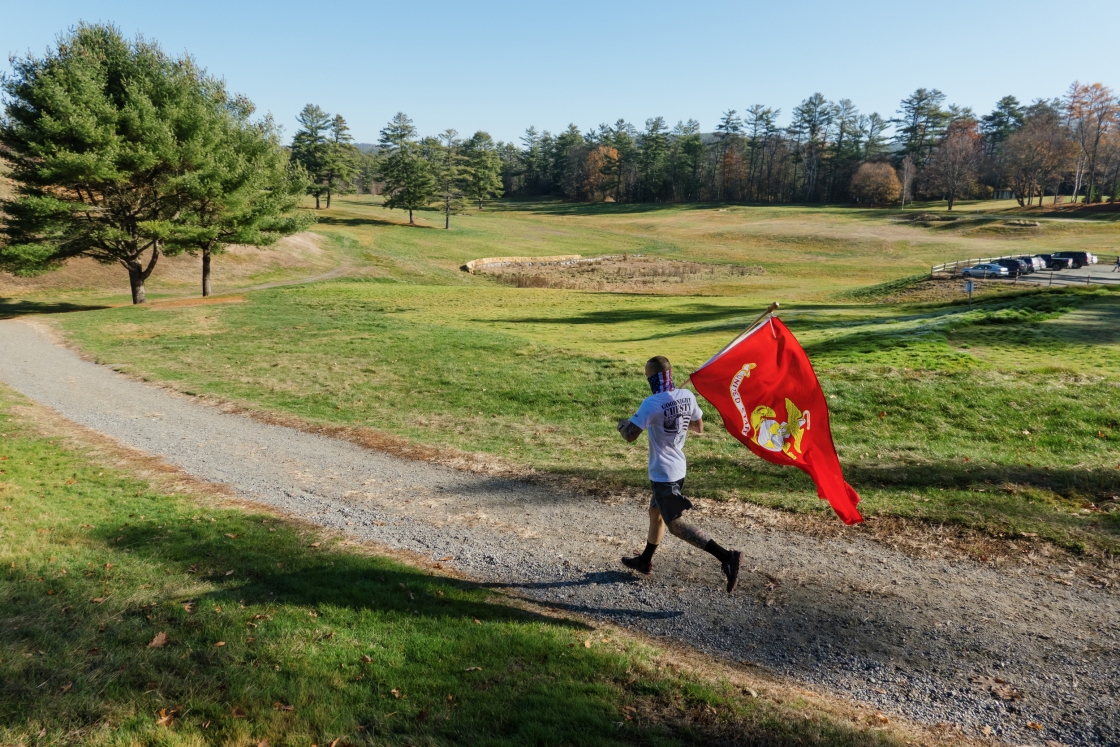 Jason Mosel running on the Hanover Golf Course carrying the Marine Corps flag
