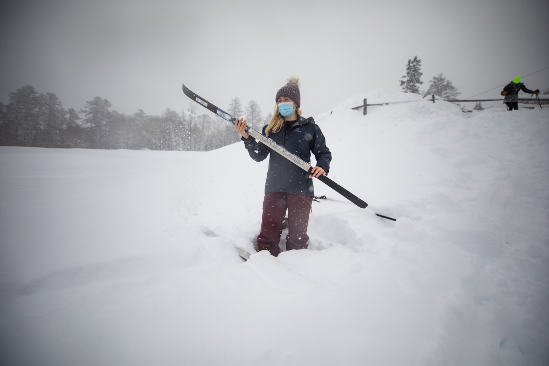 Girl holds skis in the snow on Dartmouth campus December 16, 2020
