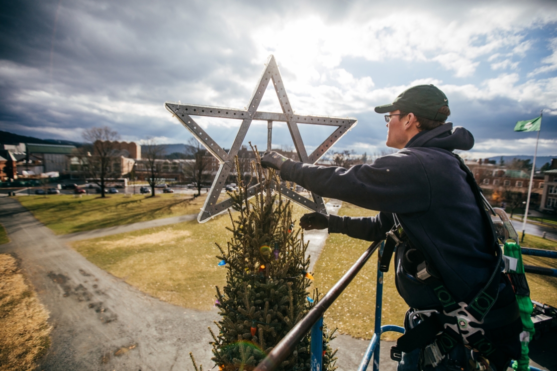 Star being placed on top of the Christmas tree on the Green