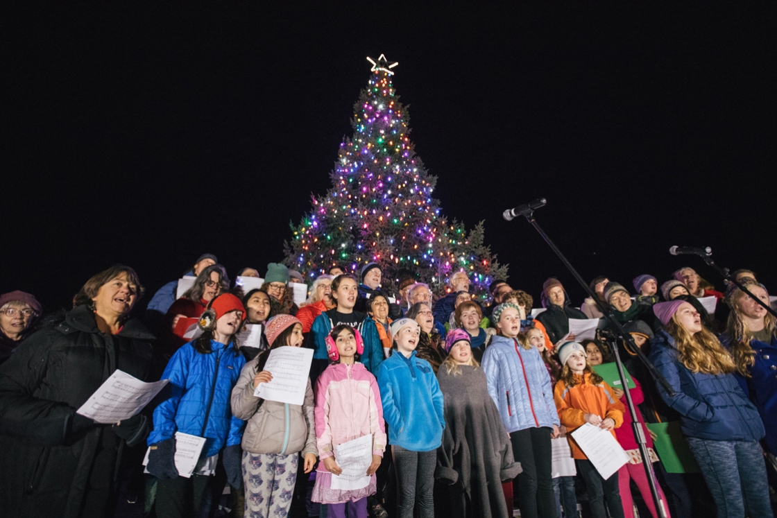Christmas carolers and lighted tree on the Green
