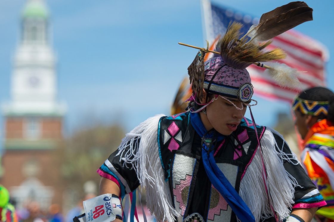 a Native American dancer in black and pink regalia with fringe and feathers