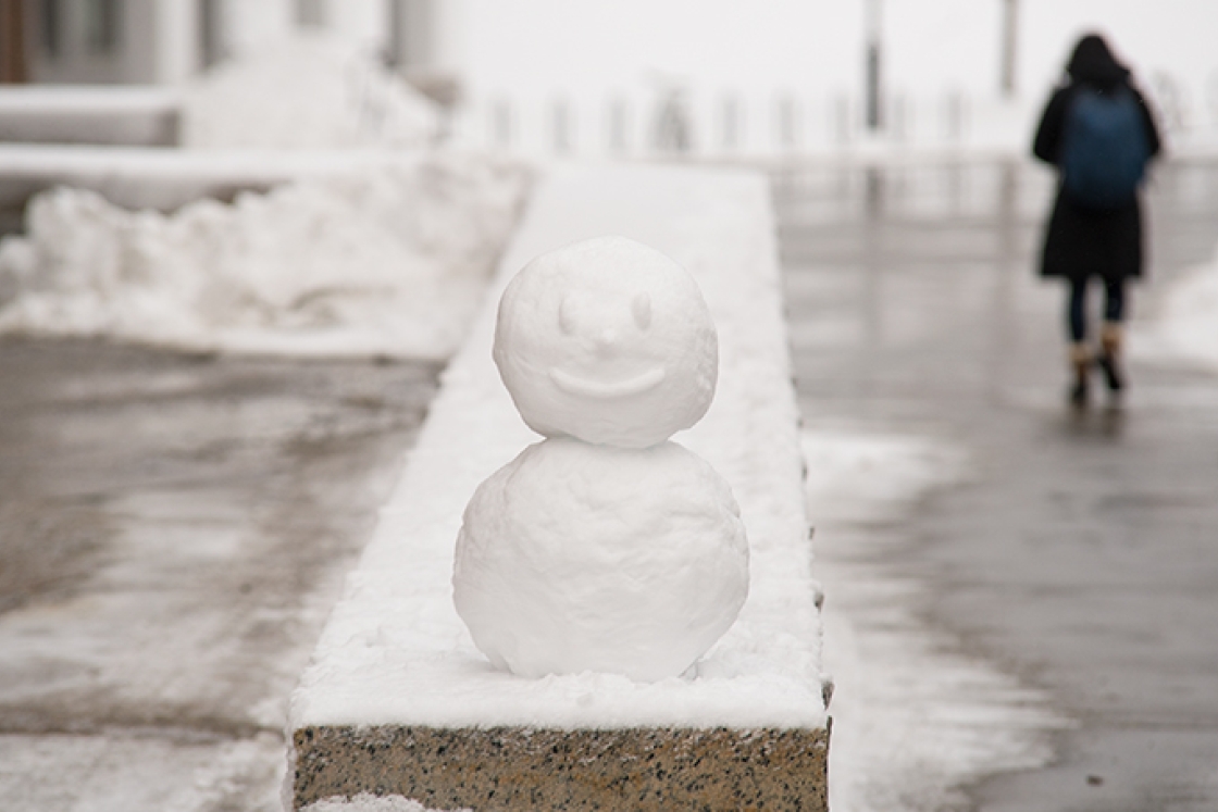 a miniature snowman sitting on a granite ledge