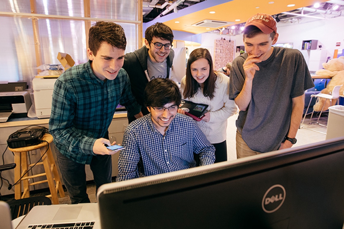 a group of students gathered around a computer