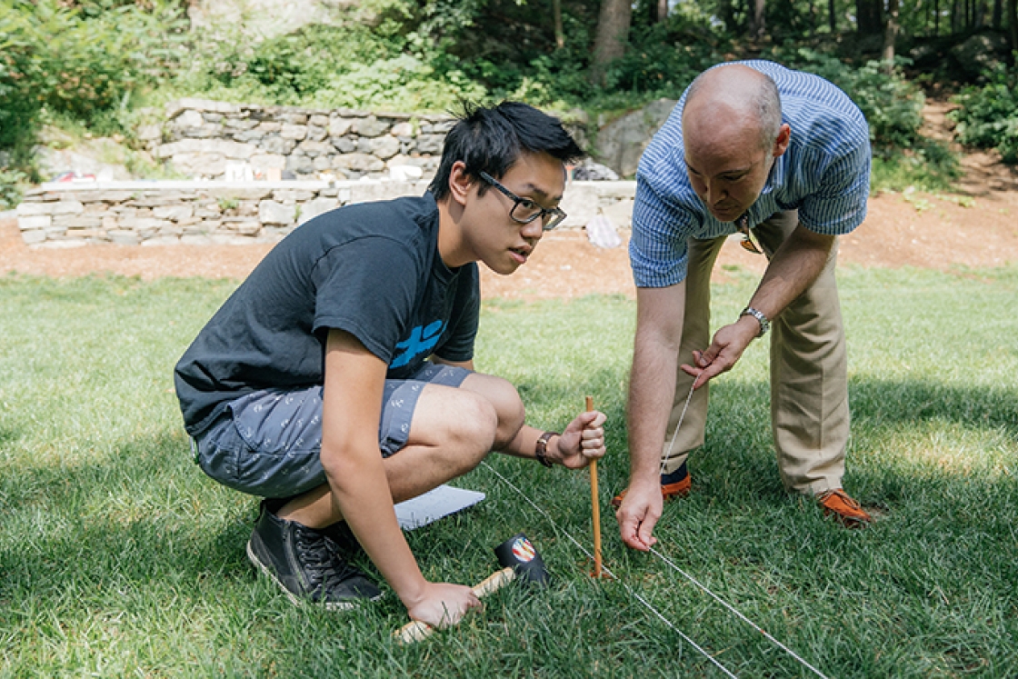 a student and professor placing string on the ground