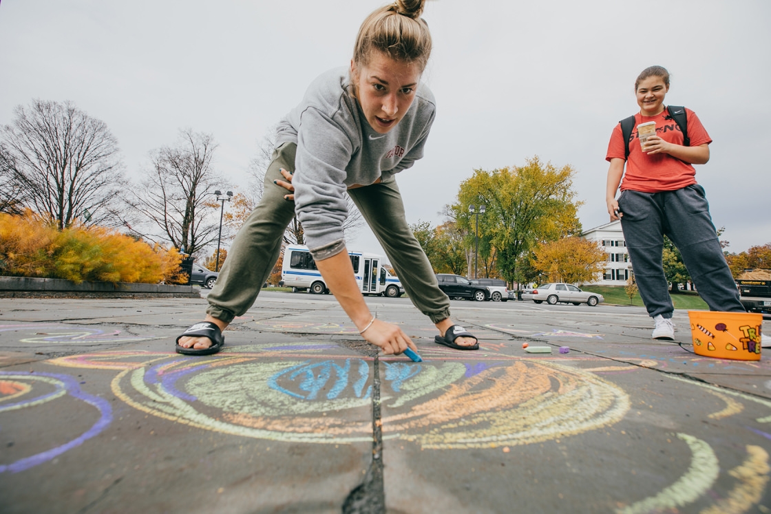 Students use chalk to draw on the sidewalk in front of the Hopkins Center