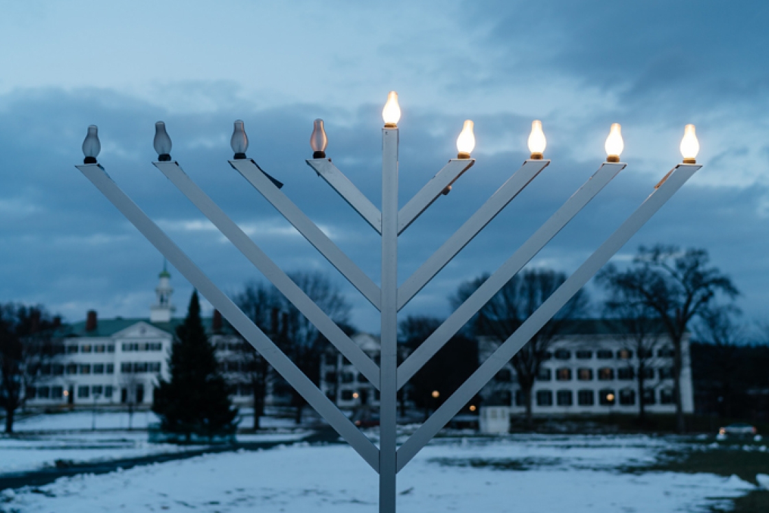 A menorah with five lit up lights on the Green at dusk.