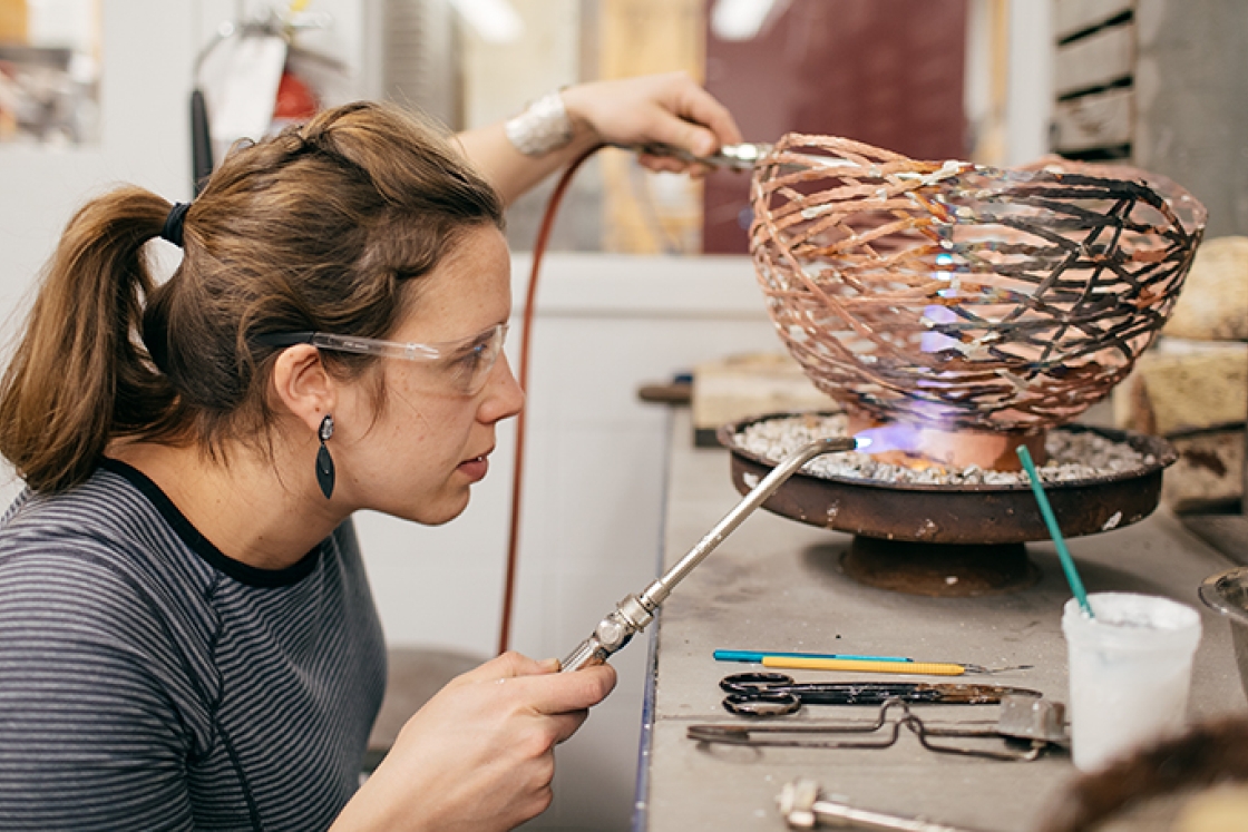 an artist welding a copper bowl together