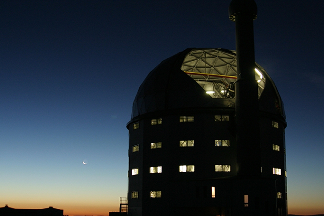a silhouette of an observatory building against a sunset sky