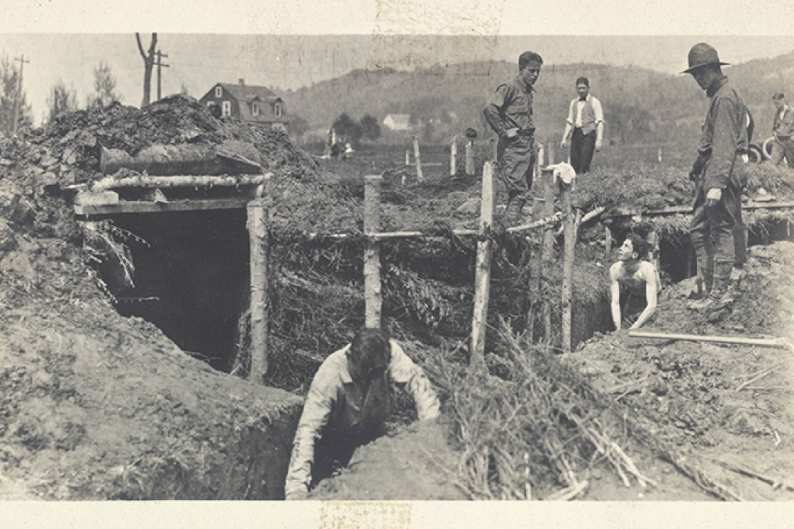 a black and white photo of students digging trenches outside