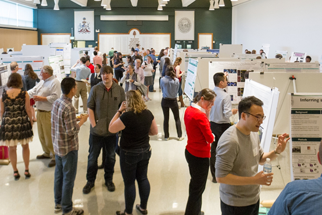 a crowd of people and displays of graduate research posters inside Alumni Hall at Dartmouth